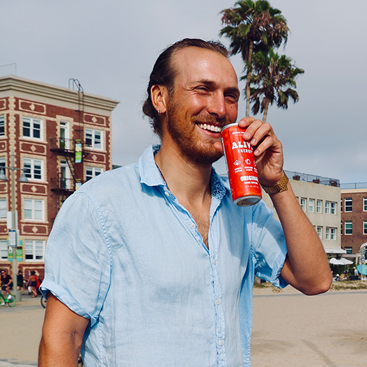 Man smiling with red Alive Energy can in hand