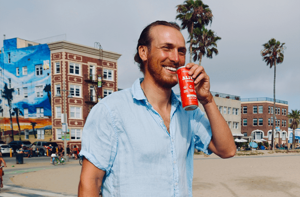 Man smiling with red Alive Energy can in hand