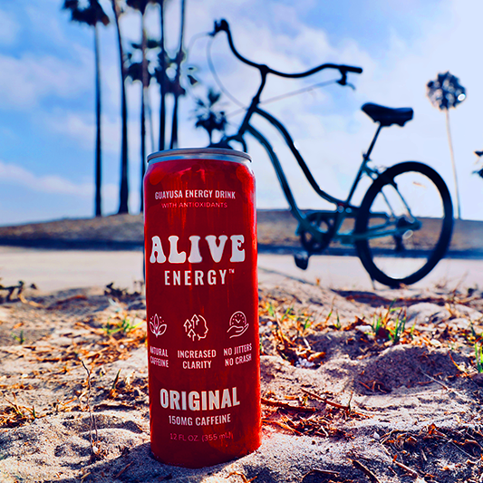Bike on sidewalk in a beach setting with red Alive Energy can in foreground