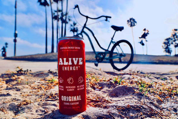 Bike on sidewalk in a beach setting with red Alive Energy can in foreground